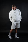 Person wearing a gray hoodie and shorts set on a black background