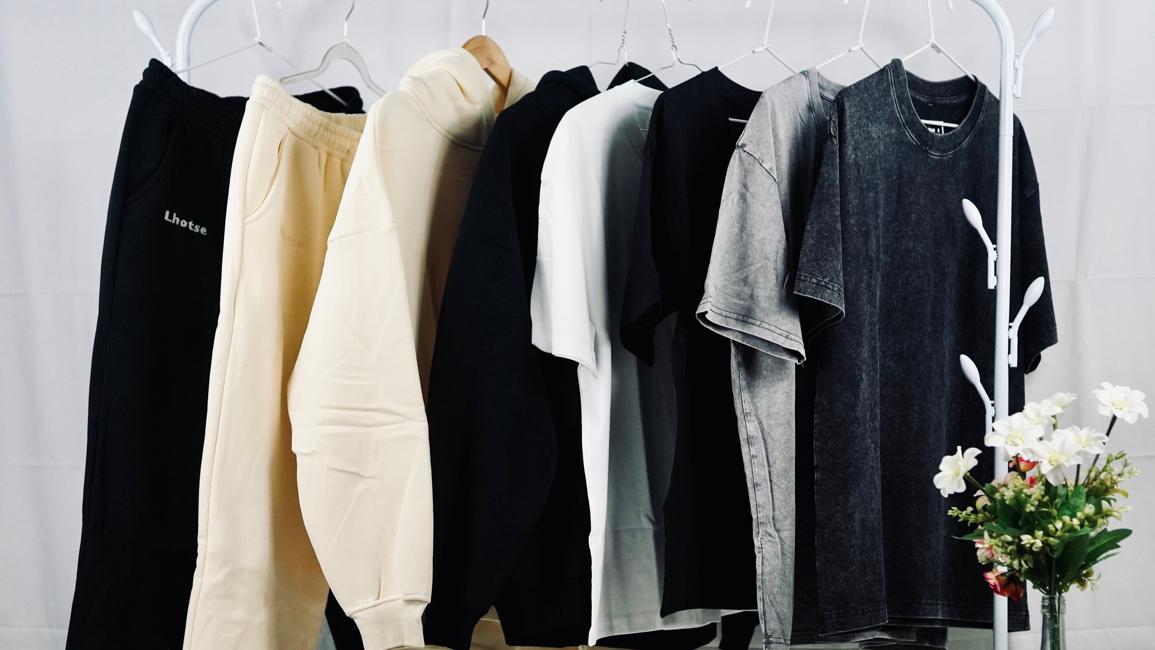 Clothing items on a rack with a vase of flowers in the background Lhotse