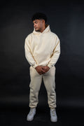 Person wearing a white hoodie and pants set against a black background