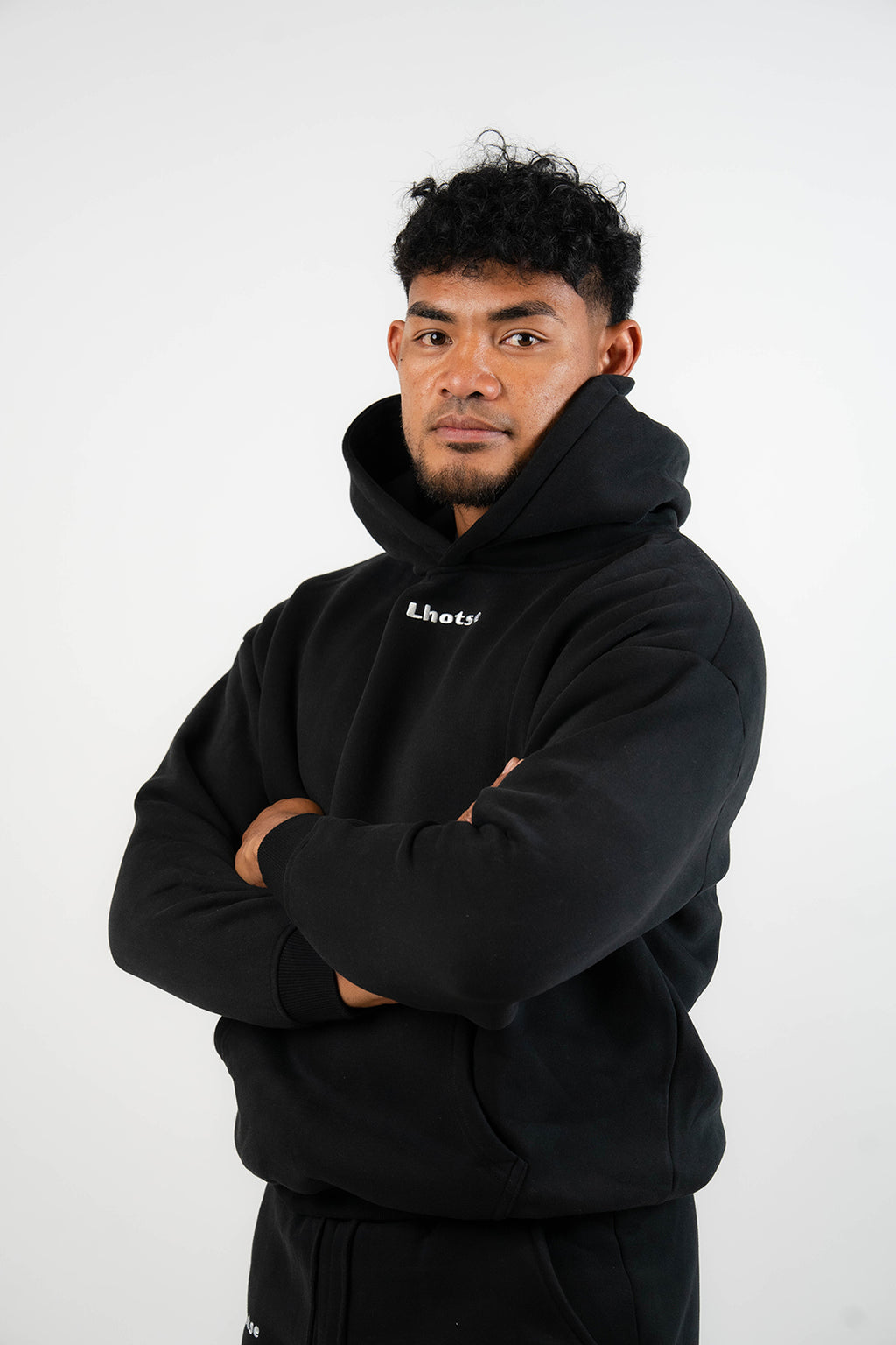 Person wearing a black hoodie with a brand logo on a white background